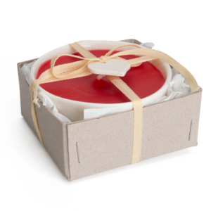 Rote Kerze in weißem Porzellanschälchen, verpackt im Karton und dekoriert mit einer weißer Schleife und einem Herzen